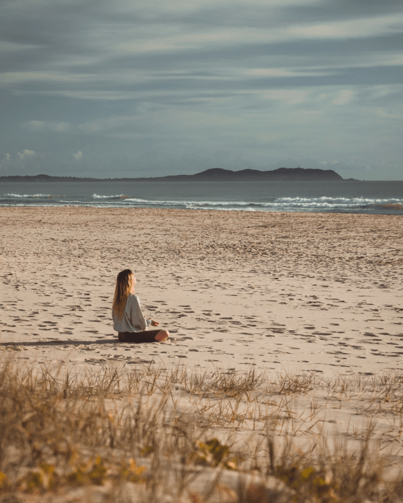 woman meditating on the beach